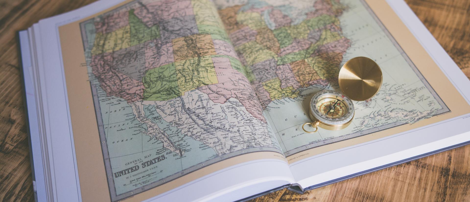 open history book with a map of the United States and a compass